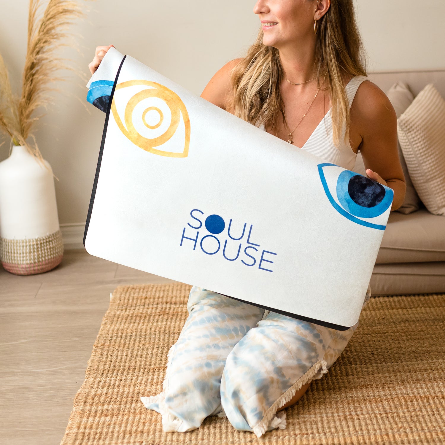 Lady holding microfiber suede yoga mat with blue and golden evil eye.